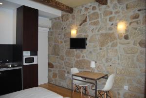 Habitación con mesa, sillas y pared de piedra. en Casa Dos Caldeireiros en Oporto