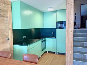 une cuisine avec des armoires bleues, une table et des chaises dans l'établissement La Durance, à Montgenèvre