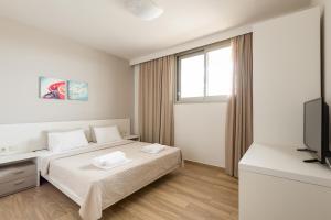 a white bedroom with a bed and a television at Afisia Villas in Sarti