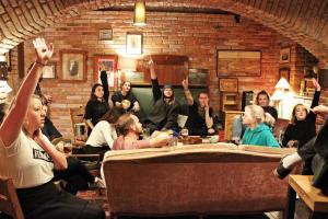 un grupo de personas sentadas en una habitación con las manos en alto en Sir Toby's Hostel, en Praga