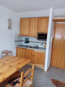 eine Küche mit Holzschränken und einem Holztisch in der Unterkunft Bilocale Fronte Piste - Appartamentiflarida Sansicario Alto in San Sicario