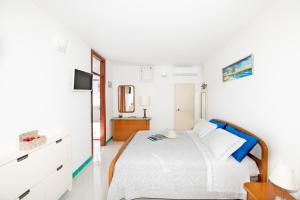 een witte slaapkamer met een bed en een televisie bij Blue Line House Positano in Positano