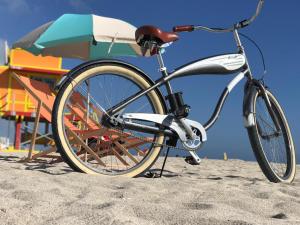 een fiets geparkeerd op het strand naast een parasol bij Century Hotel in Miami Beach
