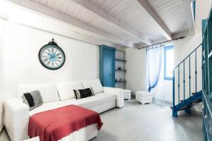 a white living room with a white couch and a clock at Le Piccole Case Bianche in Ostuni