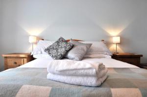 Una cama con mantas blancas y almohadas. en Penny Post Cottage, en Warton