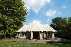 Tienda con sillas y mesas en un campo en Glamping Canonici di San Marco en Mirano