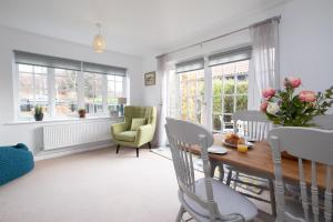 een woonkamer met een tafel, stoelen en ramen bij Bay Cottage in Thorpeness