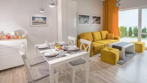 a living room with a white table and a yellow couch at Piasek i Woda Apartamenty Butikowe in Grzybowo