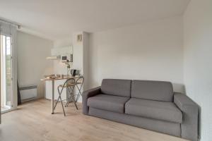 a living room with a couch and a table at City Résidence Sophia in Valbonne