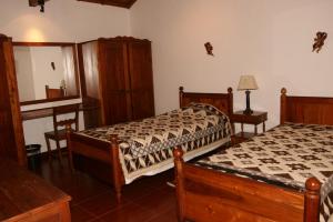 a bedroom with two beds and a table and a mirror at Quinta dos Figos "5 Trevos GOLD" in Praia da Vitória