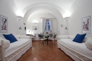 una sala de estar con 2 sofás blancos y una mesa. en Vicolo 23 House, en Atrani