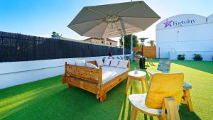 a patio with an umbrella and a couch and chairs at FBC Fortuny Resort - Adults Only in Maspalomas