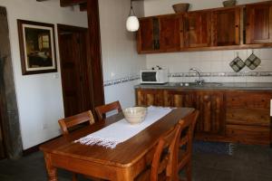 a kitchen with a wooden table with chairs and a sink at Quinta dos Figos "5 Trevos GOLD" in Praia da Vitória