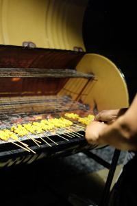 a person is cooking food on a grill at A Coral Reefs Resort Langkawi in Kuah