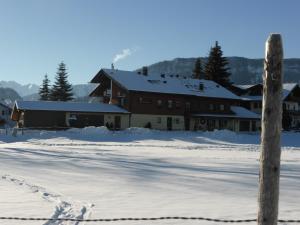 a building in the snow with footprints in the snow at Ferienhotel Silberdistel garni in Bolsterlang