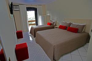 a bedroom with two beds with red pillows at Pousada Magnus in Balneário Camboriú +104 photos