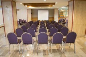 Travohotel Monterrey Histórico في مونتيري: قاعة اجتماعات مع كراسي أرجوانية وشاشة