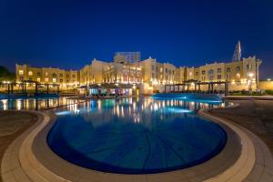 a large swimming pool in front of buildings at night at Copthorne Al Jahra Hotel & Resort in Kuwait