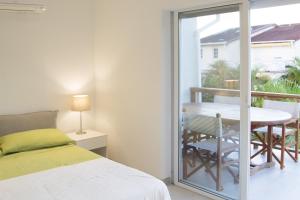 een slaapkamer met een bed en een balkon met een tafel bij Beach House Antigua in Jolly Harbour