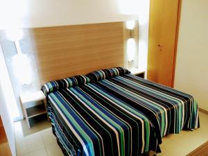 a bed with a striped blanket on it in a room at Apartamentos Jet - Adults Only in Playa d'en Bossa