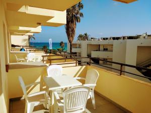 a balcony with white tables and chairs and the ocean at Apartamentos Jet - Adults Only in Playa d'en Bossa