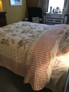 a bedroom with a bed with a floral bedspread at Wynberg House Bed & Breakfast in Swansea