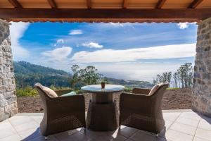 a patio with a table and chairs and a view at Rochão Village by Rent2U, Lda in Calheta