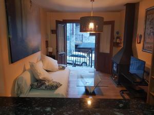 a living room with a white couch and a television at Apartamentos Nilsson, Casa Botigue, centro de Plan in Plan