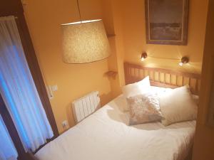 a bedroom with a bed with white pillows and a lamp at Apartamentos Nilsson, Casa Botigue, centro de Plan in Plan