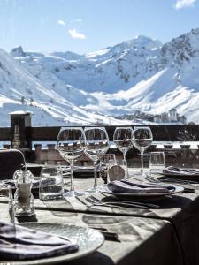 a table with wine glasses on a table with snow covered mountains at Hôtel les Campanules by Les Etincelles in Tignes