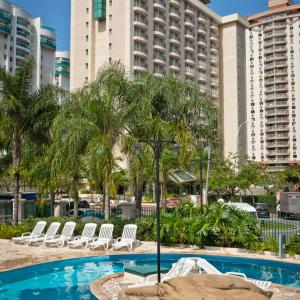 a swimming pool with chairs and a building at Bourbon Barra da Tijuca Residence in Rio de Janeiro