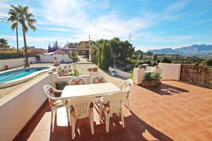 eine Terrasse mit Tisch und Stühlen und einem Pool in der Unterkunft El Ventorrillo - holiday home with stunning views and private pool in Benissa in Benissa