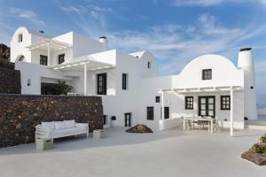 a white house with a stone wall at Aenaon Villas in Imerovigli