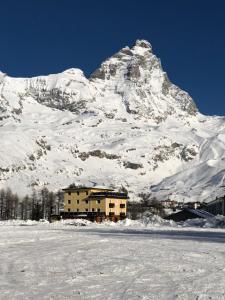 een gebouw voor een met sneeuw bedekte berg bij Monolocale Cielo Alto in Breuil-Cervinia