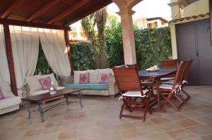 eine Terrasse mit einem Tisch, Stühlen und einem Sofa in der Unterkunft Villa Eva Luxury Villasimius in Villasimius