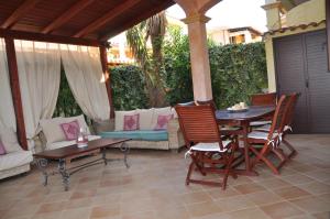 a patio with a table and chairs and a couch at Villa Eva Luxury Villasimius in Villasimius