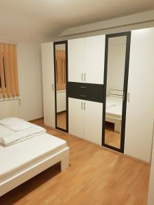 a bedroom with white cabinets and a large mirror at Ferienwohnungen Albstadt in Albstadt