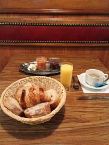 a table with a basket of bread and a glass of orange juice at L'Hôtel du Mouton blanc in Fresne-Saint-Mamès