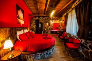 a bedroom with a red bed and a table and chairs at Patriko Mountain Chalet in Palaios Agios Athanasios