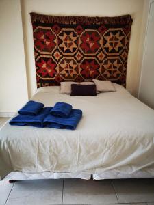 Una cama con dos almohadas azules encima. en Apartamentos Itati en General Sarmiento