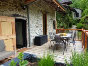 eine Holzterrasse mit einem Tisch und Stühlen darauf in der Unterkunft la grange de clotilde in Siguer