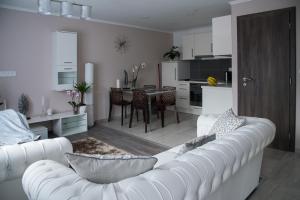 a living room with a white couch and a kitchen at Orchidea Apartman in Balatonkenese