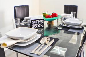 a glass table with plates and utensils on it at Garzota Suites Airport Balcony in Guayaquil +24 photos