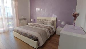a white bedroom with a bed and two tables at La casa di Lucia in Bergamo
