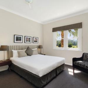 a bedroom with a large white bed and a chair at Peppers Craigieburn Resort in Bowral