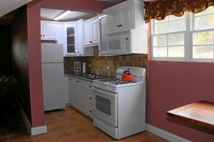 a kitchen with white cabinets and a stove top oven at CosyNest in Basseterre