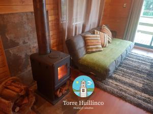 sala de estar con estufa de leña y sofá en Cabañas Torre Huillinco, en Huillinco