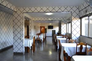 ein Esszimmer mit Tischen, Stühlen und einem Spiegel in der Unterkunft Império Hotel in Caçu
