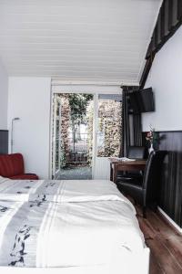 a bedroom with a bed and a desk and a window at Hotel 't Welink in Dinxperlo