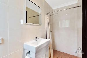 a white bathroom with a sink and a shower at Fossicker Caravan Park in Glen Innes